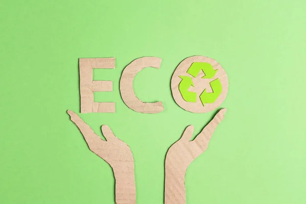 Cardboard eco word with recycle symbol in hands silhouette on gr — Stock Photo, Image