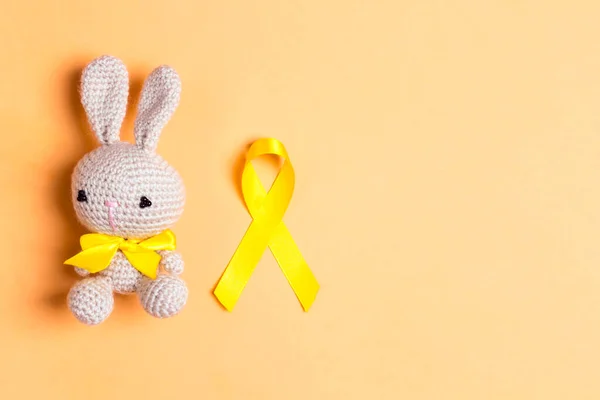 Barncancer Medvetenhet Golden Ribbon Med Leksak Kanin Gul Bakgrund Kopiera — Stockfoto