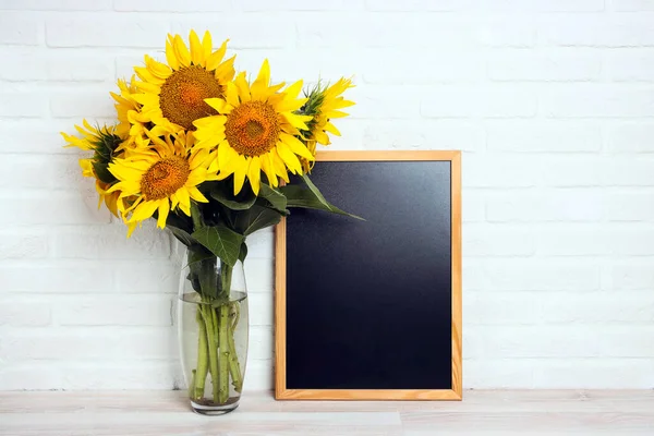 A bouquet of sunflowers in a vase with red paper shopping bag against the white brick wall. Copy space for text. Shopping and sale concept.