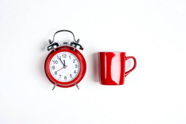 Kırmızı klasik çalar saat ve beyaz arka planda kırmızı kahve fincanı. Uyanmak ya da zaman kavramını kırmak. 
