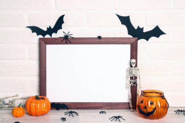 Beyaz tuğla duvara karşı cadılar bayramı süslemeleri olan boş ahşap çerçeve. Cadılar bayramı geçmişi. Tasarım için alanı kopyala.