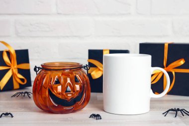 Cadılar Bayramı beyaz kahve kupası, balkabağı Jack fener şamdanı ve hediyeler. Metin veya tasarım için boşluk.