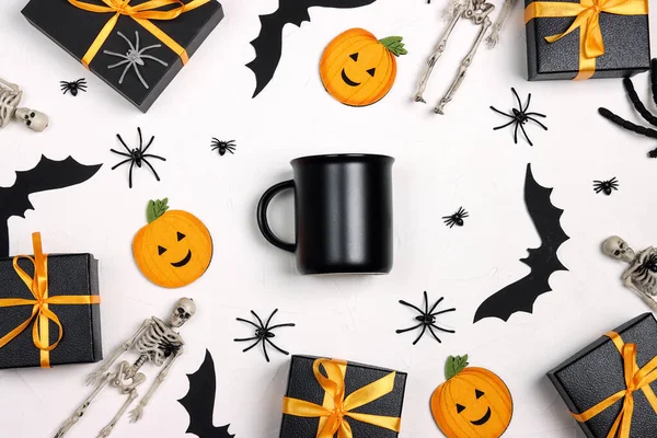 Black mug surrounded by Halloween decorations and gifts. Space for text or design.