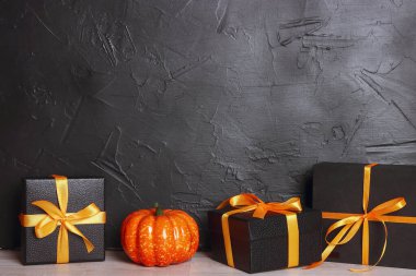 Cadılar Bayramı arkaplanda hediyeler ve siyah bir duvara yapıştırılmış balkabağı var. Metin için alanı kopyala.