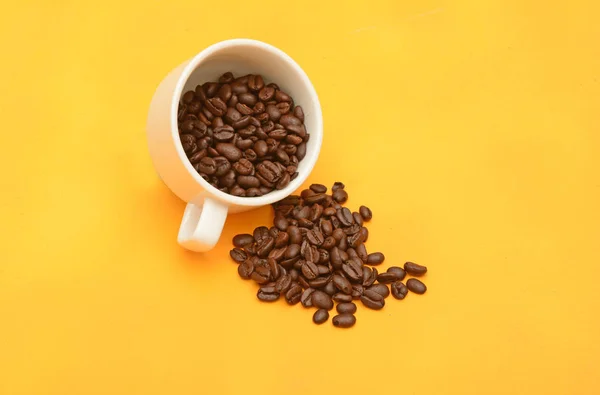 Kaffebönor med tekopp, naturliga frön på gul bakgrund — Stockfoto