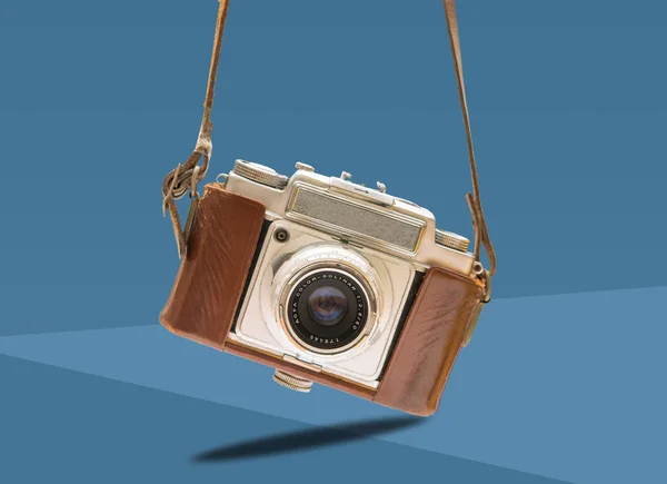 Fotocamera vintage con un cinturino in pelle appeso sul blu — Foto Stock