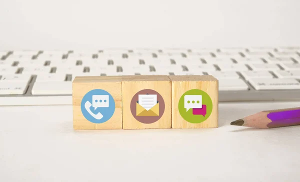 Communications icons on wooden blocks with keyboard, Contact Us concept — Stock Photo, Image