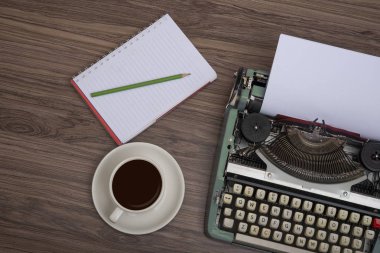 Kahve fincanı ve not defteri üst görünümü ile eski ahşap masada daktilo