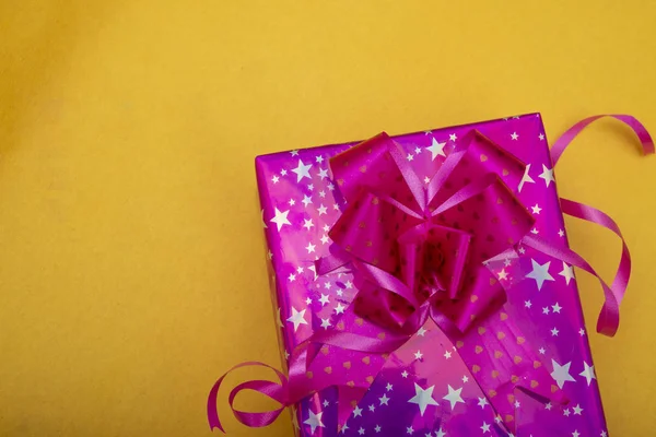 Caixa de presente de natal de cor rosa no fundo de cor amarela, copie o banner do espaço — Fotografia de Stock