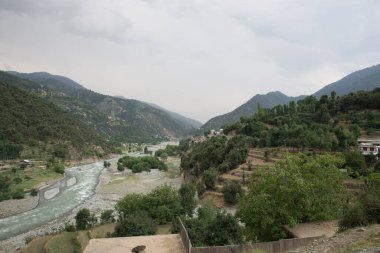 Bulutlu gökyüzü arkaplanlı güzel yeşil vadinin fotoğrafı. Metnin için kopya alanı var.