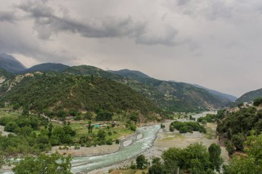 Bulutlu gökyüzü arkaplanlı güzel yeşil vadinin fotoğrafı. Metnin için kopya alanı var.