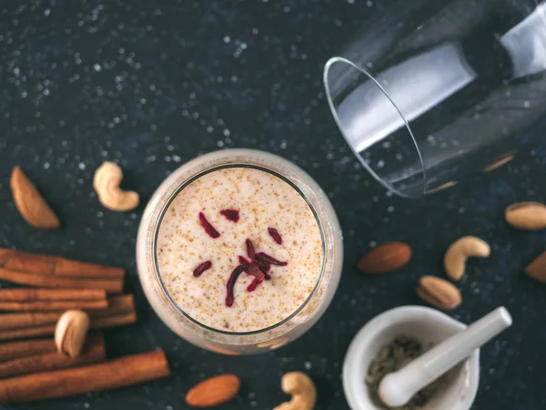 Thandai or Sardai cold drink made during Holi festival. Cold milk drink in glass, with ingredients - nuts and spices. Copy space