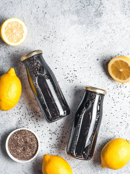 Detox activated charcoal black chia water or lemonade with lemon. Two bottle with black chia infused water. Detox drink idea and recipe. Vegan food and drink. Top view. Copy space for text. Vertical.