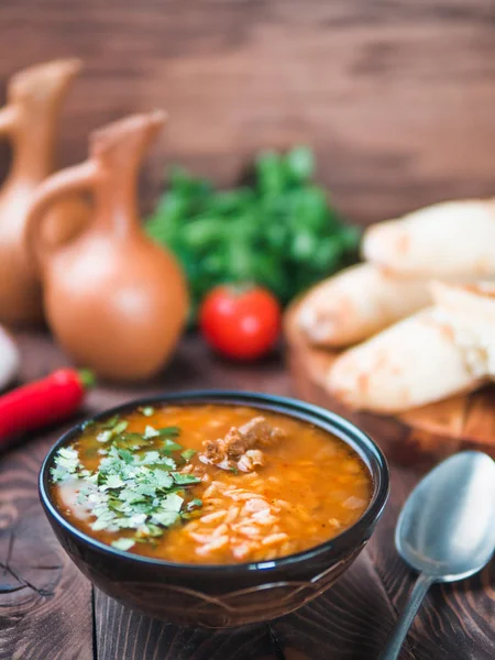Traditional Georgian kitchen-soup Kharcho with meat,rice and fresh cilantro.Spicy soup Kharcho on wooden table with traditional bread Shotis Puri,vintage wine jar,vegetables.Copy space text. Vertical. — Stock Image Traditional Georgian Kitchen Soup Kharcho Meat Rice Fresh Cilantro Spicy Stock Image