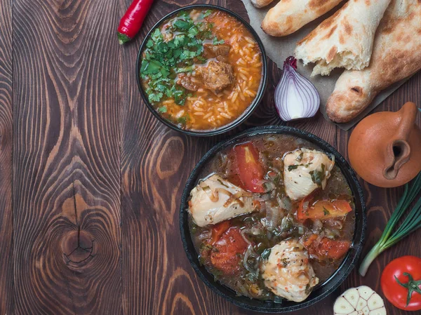 Traditional Georgian kitchen - spicy Kharcho soup and chicken Chachochbili, traditional bread Shotis Puri, vintage wine jar, fresh vegetables on wooden table. Copy space for text. Top view — Stock Image Traditional Georgian Kitchen Spicy Kharcho Soup Chicken Chachochbili Traditional Bread Stock Picture