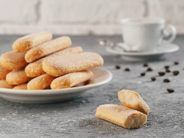 Italian cookie savoiardi and cup of coffee. Close up view of ladyfinger biscuit cookie on gray concrete background. Copy space.