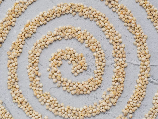 Grain of quinoa. Uncooked raw quinoa abstract spiral, lying on gray concrete background. Healthy vegan food concept and pattern. Top view or flat lay