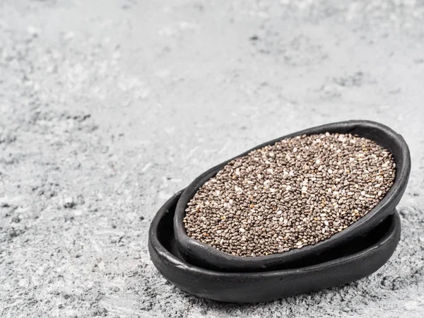 Close up view of chia seeds in trendy plate with copy space. Chia seed on gray concrete textured background. Healthy food and diet concept