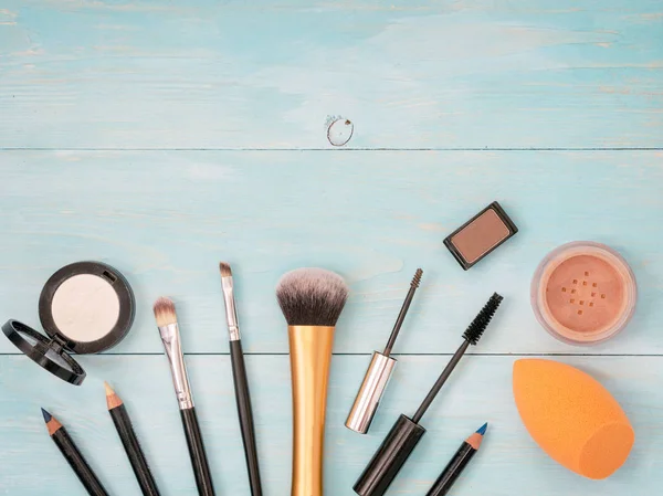 Set of make up on turquoise wooden background. Mascara brush, eyebrow gel brush, pencil, eyeshadow, sponge and brushes. Mock up with copyspace. Shallow DOF