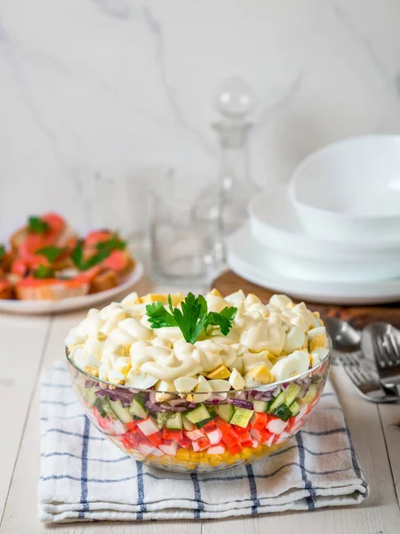Layered crab salad with corn, cucumber, rice