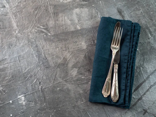 Cutlery on emerald linen napkin, copy space