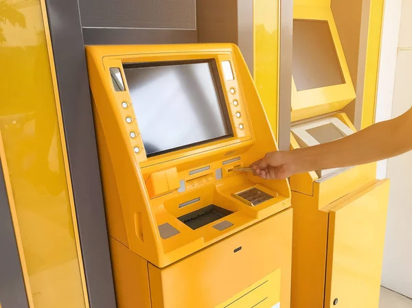 Man\'s hand is inserting an ATM card in a bank cash machine.