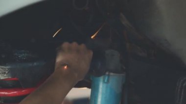 Teknisyen demir öğütmek için bir elektrikli taşlama makinesi kullanıyor.