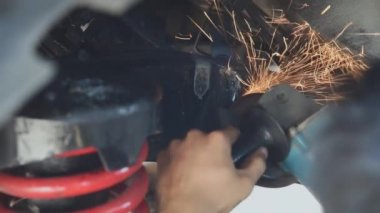 Teknisyen demir öğütmek için bir elektrikli taşlama makinesi kullanıyor.