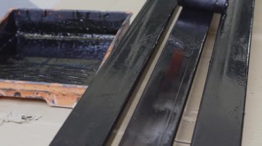 Siyah boya silindiri üzerinde çelik çubuk kullanarak bez eldiven, ressam giyer.