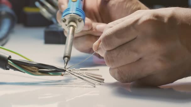 電気技師は ハンダ付け鉄を使用してワイヤを金属ピンに接続し ハンダ付けリードを使用しています — ストック動画