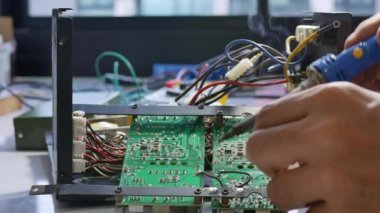 Elektronik teknisyen elektrik kablolarını elektronik bir cihazın ana kartına lehimliyor..