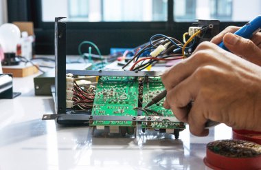 Elektronik teknisyen elektrik kablolarını elektronik bir cihazın ana kartına lehimliyor..