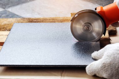 Beyaz bez eldiven giyen inşaat işçisi taşları elektrikli öğütücüyle kesiyormuş..