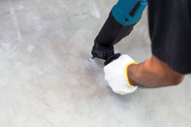 İnşaat işçileri beton duvarlarda delik açmak için elektrikli matkap kullanıyorlar..