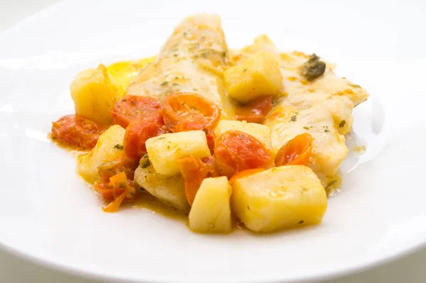 fish dish, cod with tomato, potatoes and capers, cooked in a pan.