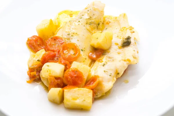 fish dish, cod with tomato, potatoes and capers, cooked in a pan.