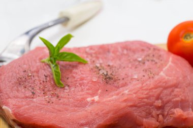 kiraz domates ve fesleğen yaprağı ile kesme tahtası üzerinde ham sığır eti biftek