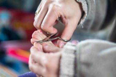 Anne kızının tırnaklarını kesiyor.