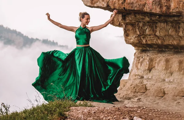 Bir uçurumun kenarında dans uzun yeşil elbise giyen güzel kadın. Mezmay. Rus dağlar.