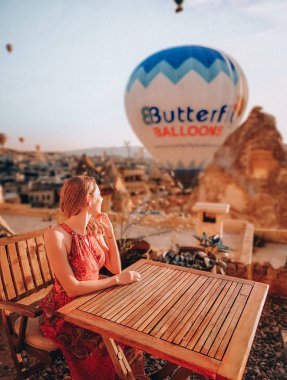 Arka planda bir büyük hava balonu ile güzel sabah Kapadokya. Kadın terasta.