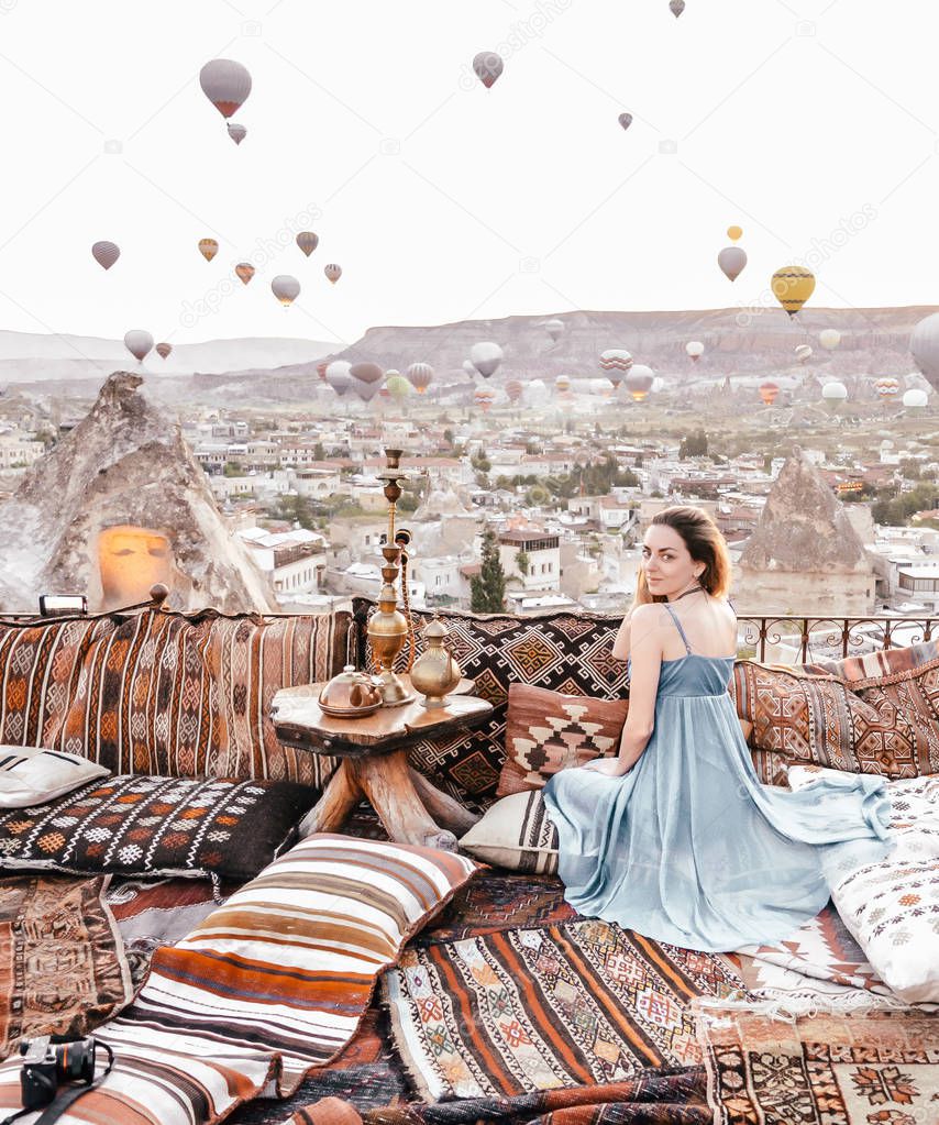 Morning view in Cappadocia. Terrace view in Goreme woman with hot air balloons and carpets in Turkey