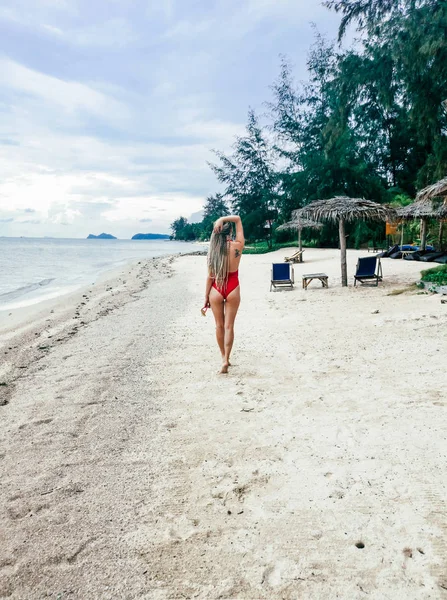 Koh Samui, Tayland kırmızı mayo giyen sahil boyunca yürüyen güzel genç kadın