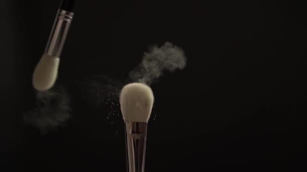 Duas escovas de maquiagem com pó em um fundo escuro, câmera lenta — Vídeo de Stock