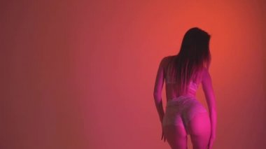 Kız dans turuncu bir arka plan üzerinde beyaz iç çamaşırı. Ağır çekim 60fps