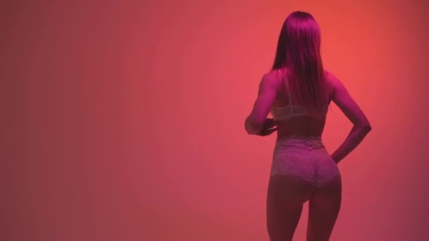 Ragazza in biancheria intima bianca che balla su uno sfondo arancione. Movimento lento 60fps — Video Stock