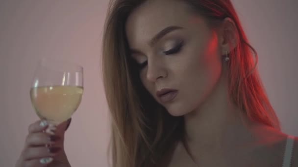 La chica bebe vino blanco, primer plano y luz de fondo roja. .. Cámara lenta 60fps — Vídeos de Stock