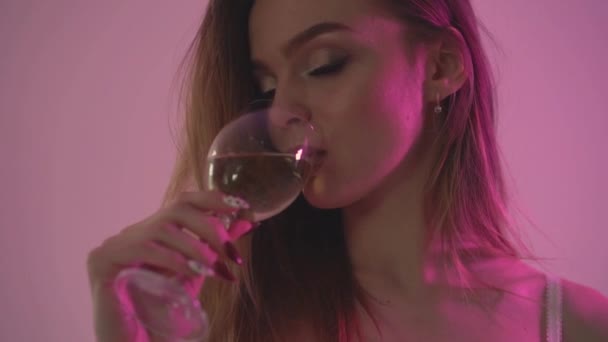 Dziewczyna pije wino białe, zbliżenie i czerwonego podświetlenia. . Zwolnionym tempie 60fps — Wideo stockowe
