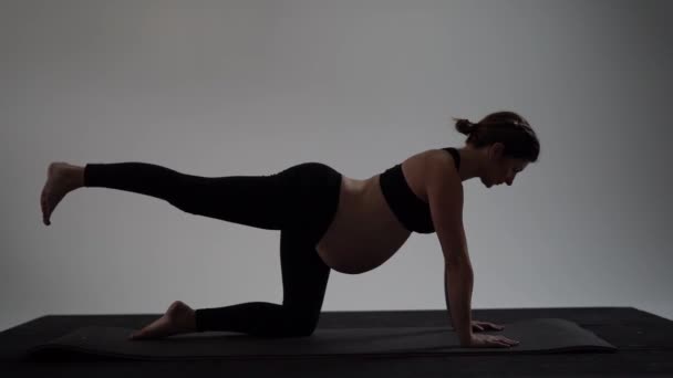 Chica morena embarazada haciendo yoga. Estilo auténtico con luz natural y sombras . — Vídeo de stock