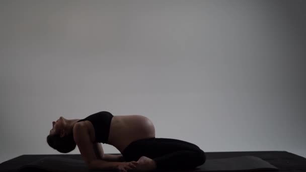 Ciężarna brunetka dziewczyna robi jogę. Autentyczny styl z naturalnym światłem i cieniami. — Wideo stockowe