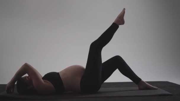 怀孕的黑发女孩做瑜伽。具有自然光线和阴影的正宗风格. — 图库视频影像